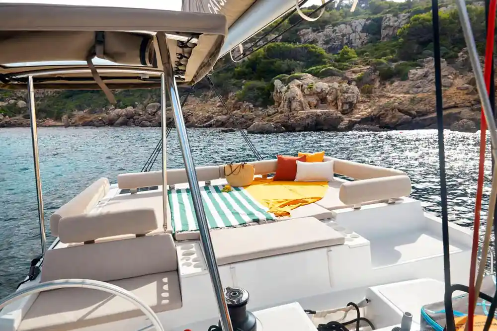 Boat deck with striped cushions and rocky coastal cliffs beyond