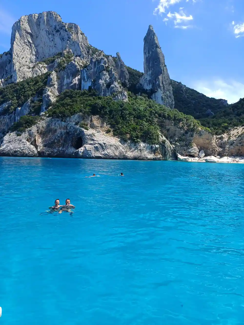 Distinctive rock formations with swimmers in turquoise sea