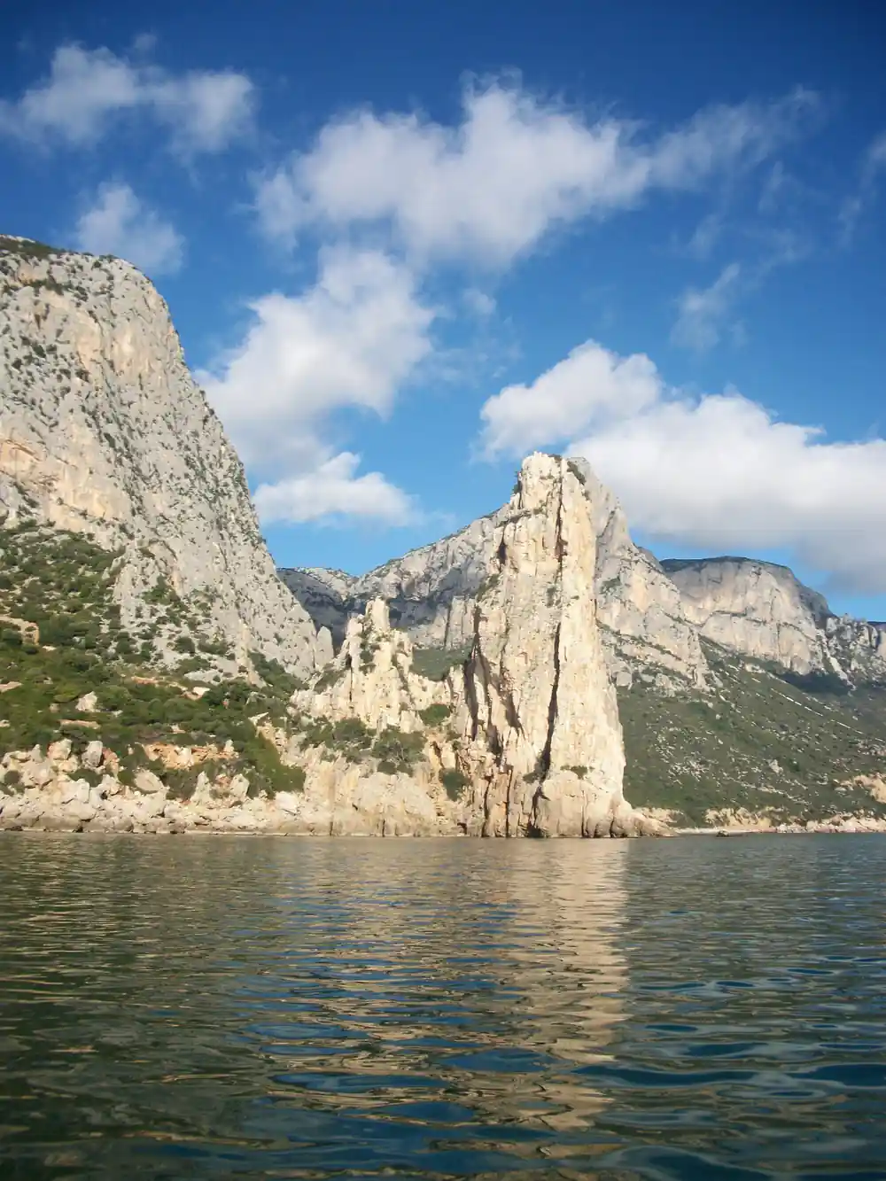 Distinctive tall rocky pinnacle rising from clear turquoise water