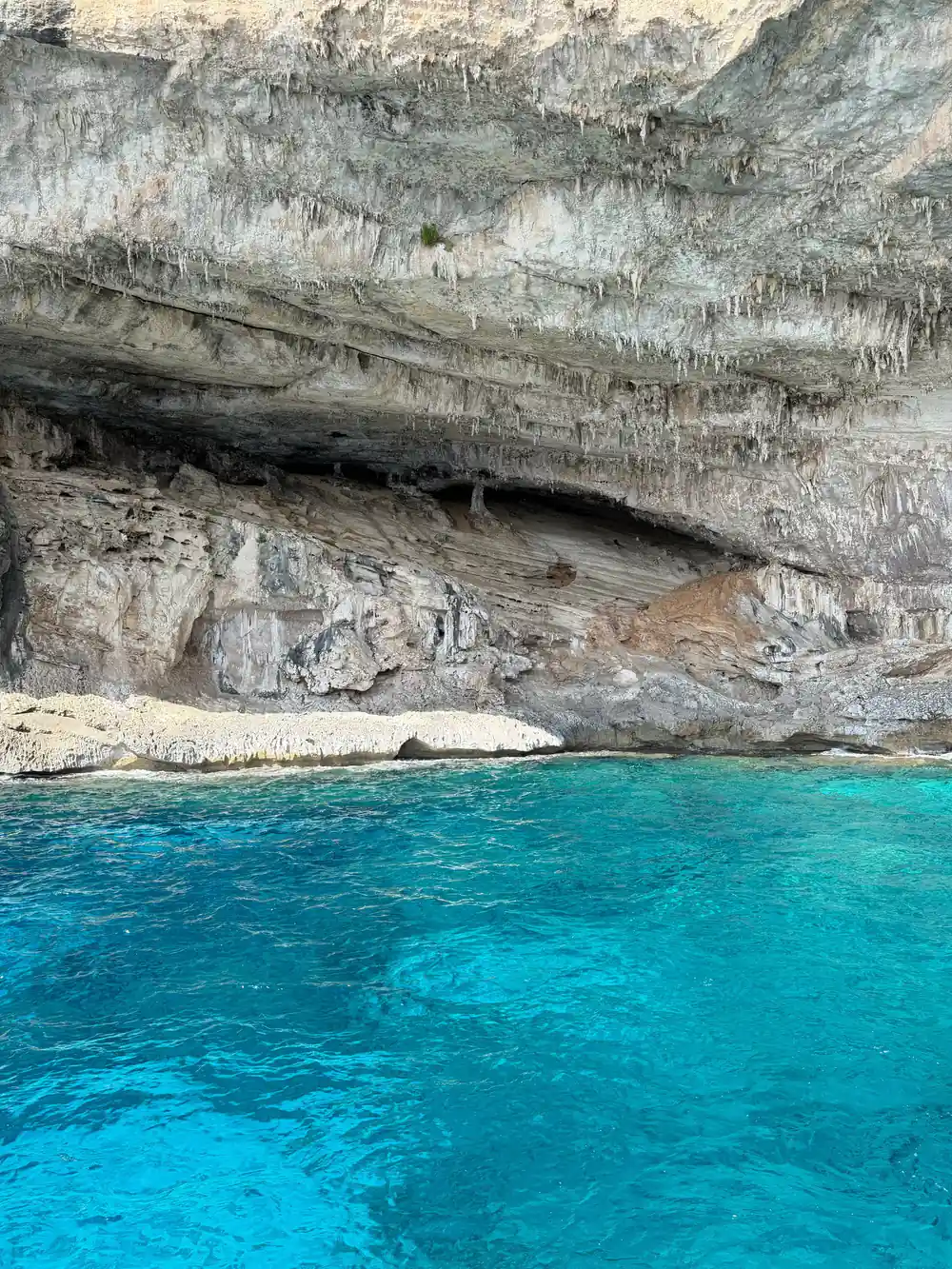 Large sea cave entrance in white rock face with turquoise water