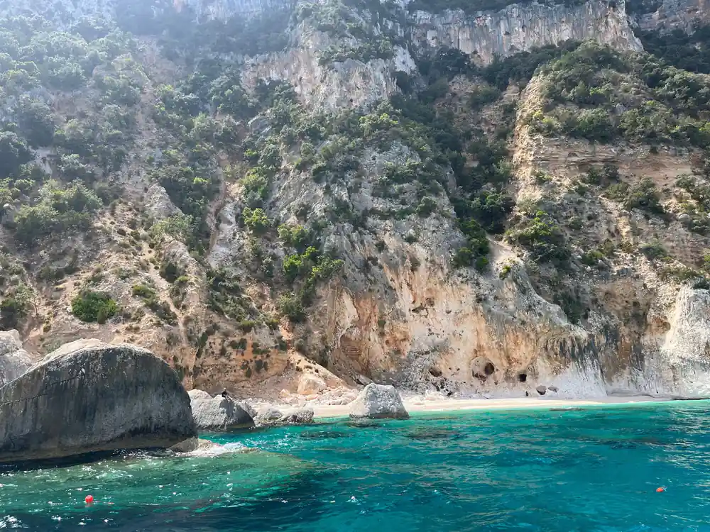 Limestone cliffs with vegetation above small beach and turquoise water