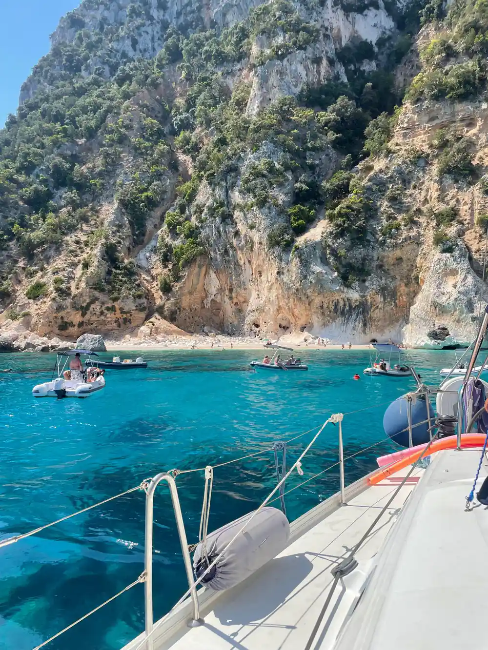 Multiple small boats anchored below steep rocky mountain
