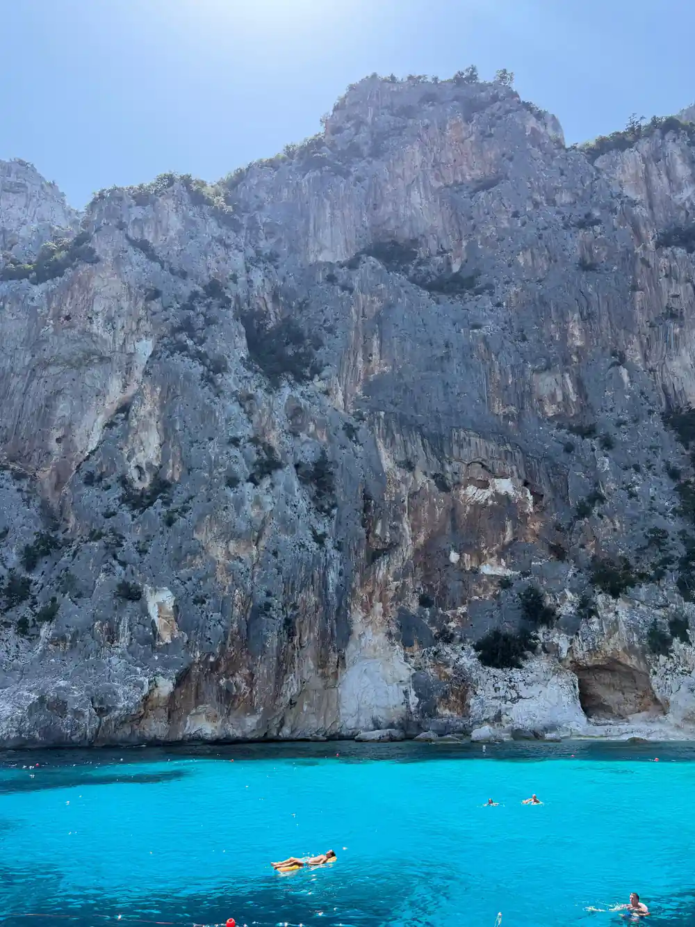 Tall columnar rock formations with person swimming in turquoise sea