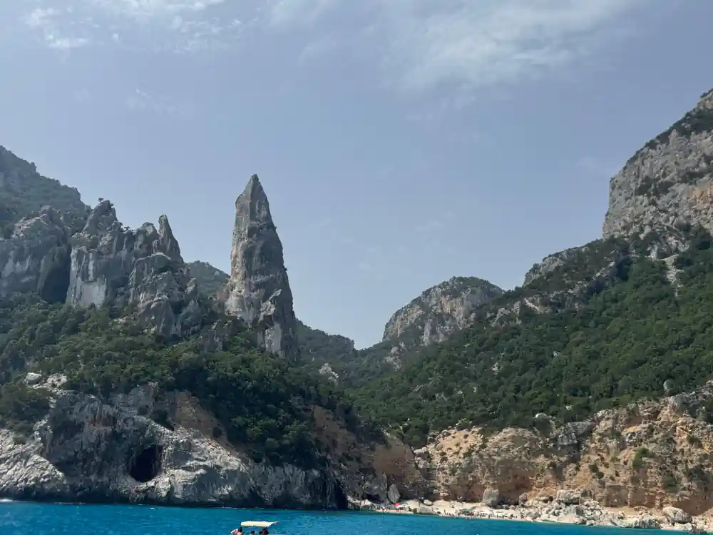 Tall rocky mountain peaks and cliffs with sea and boat below