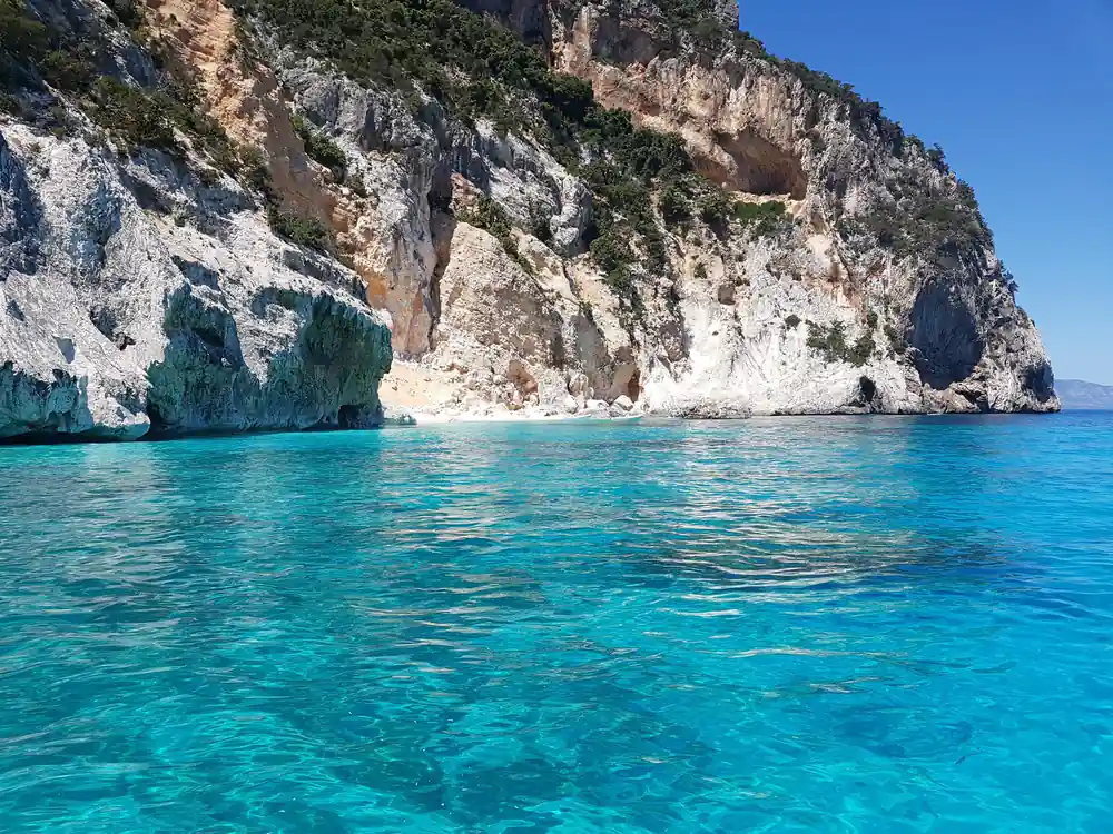Tall white limestone cliff rising from turquoise mediterranean sea