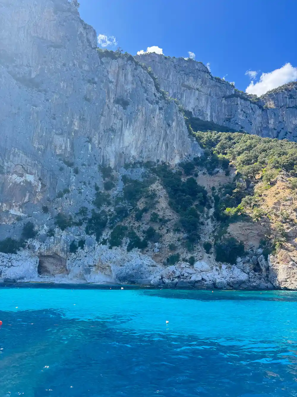 Vertical white limestone cliff face dropping to turquoise water