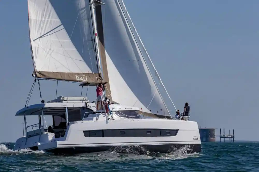White catamaran sailboat with full sails in blue ocean